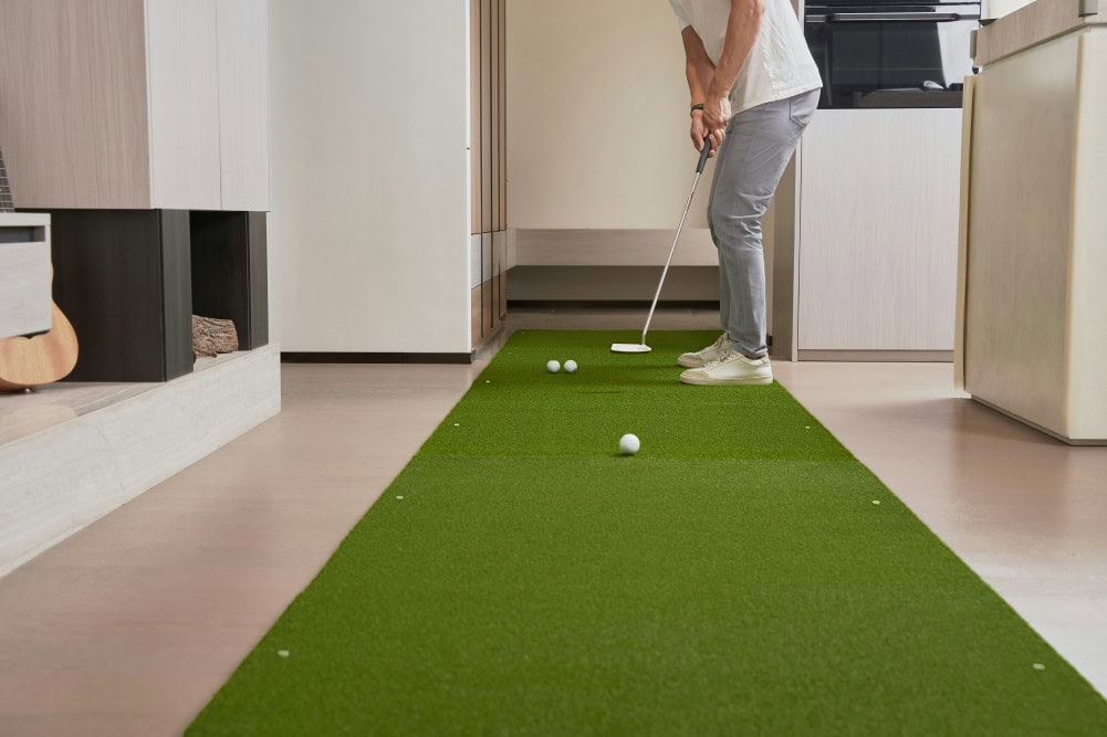 Golfeur dans son salon avec un practice de golf maison