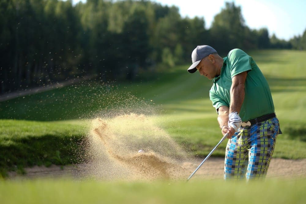 Golfeur en mode de jeu foursome se sortant d'un bunker au golf