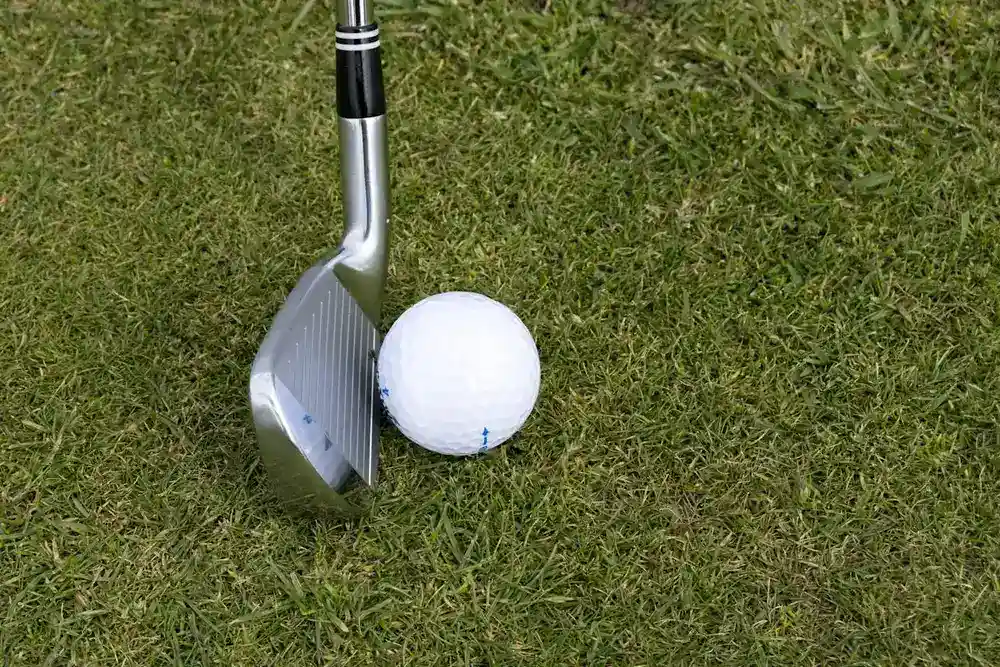Wedge de golf posé sur l'herbe à côté d'une balle : bounce semelle contact loft wedge golf