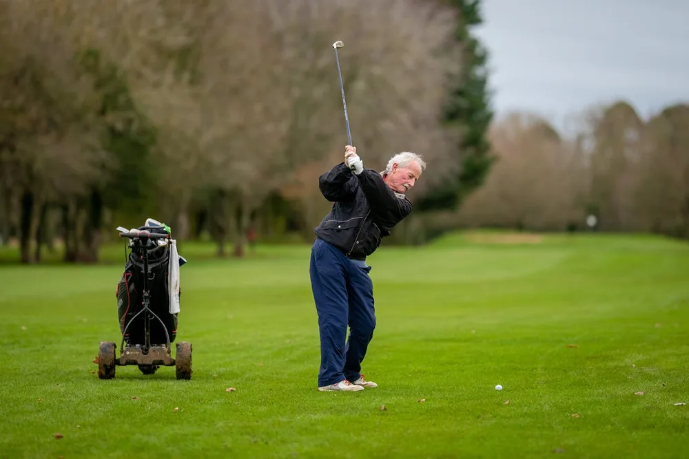 Senior golfeur en plein swing sur parcours verdoyant — bienfaits golf muscles tronc et dos