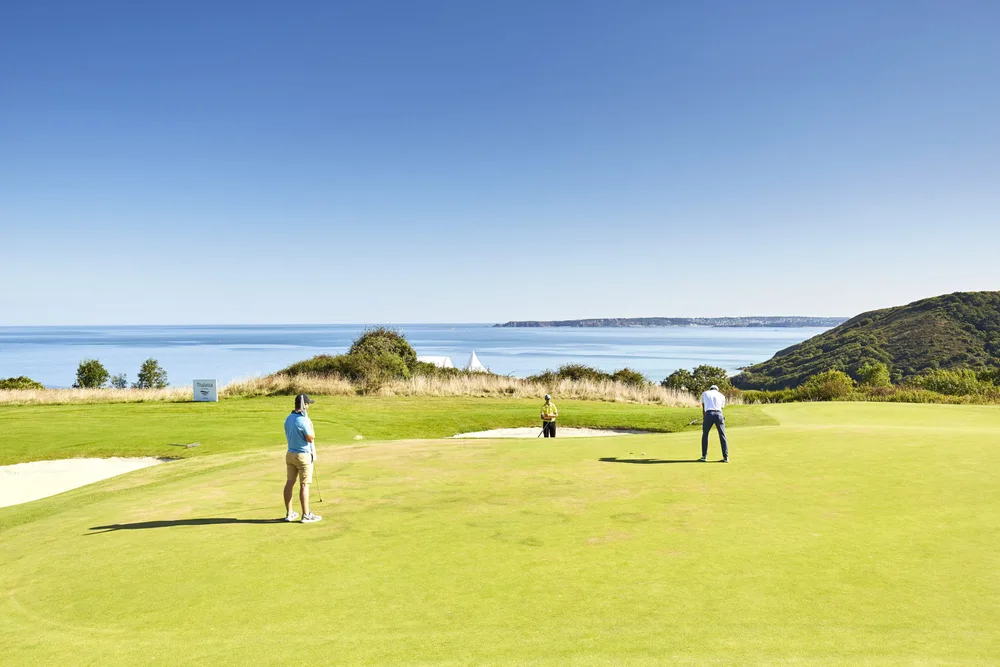 Golfeurs sur le green de Pléneuf-Val-André face à l'océan – parcours golf Bretagne Côtes-d'Armor