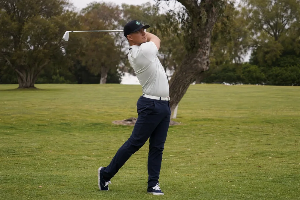 Golfeur en tenue élégante polo et pantalon technique sur le parcours – tenue golf dress code