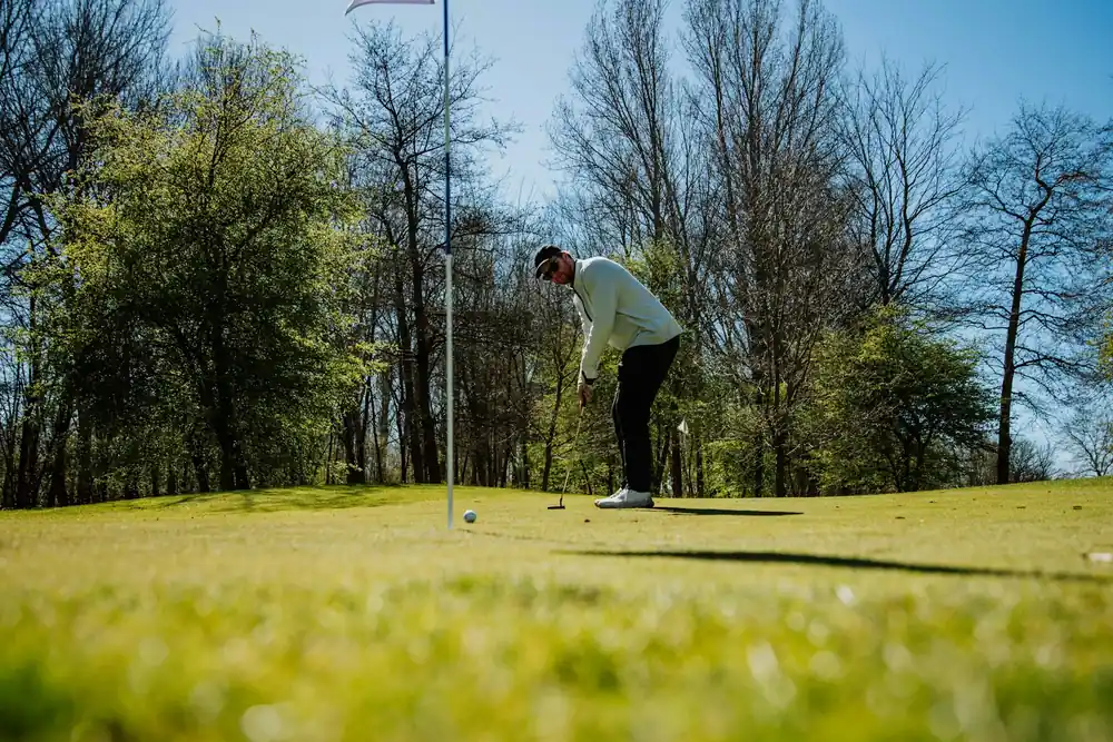 Golfeur en position de putting face au drapeau sur le green, alignement golf au putter