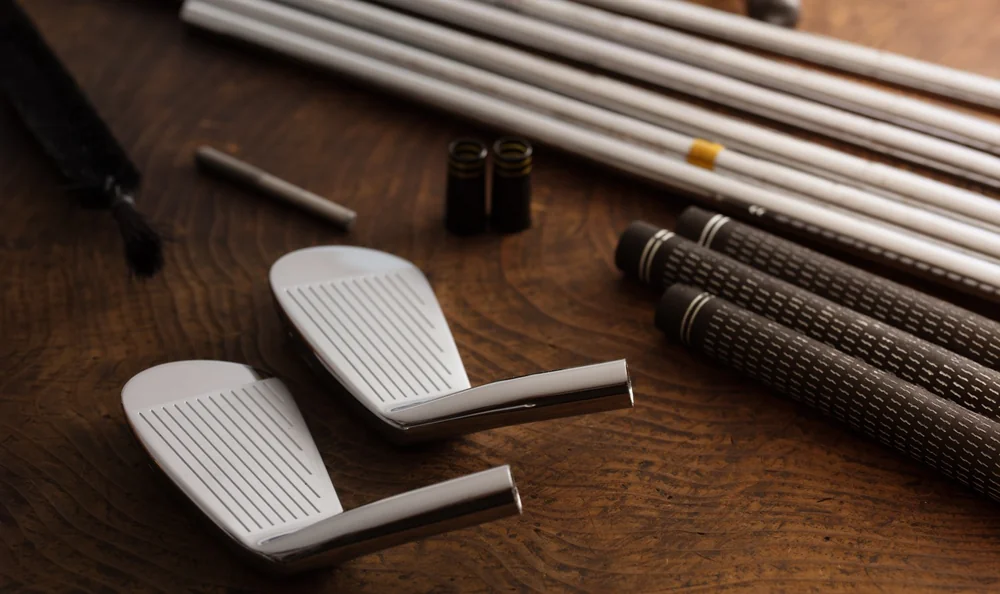 Têtes de fers, shafts et grips séparés sur établi, éléments du fitting de clubs golf occasion