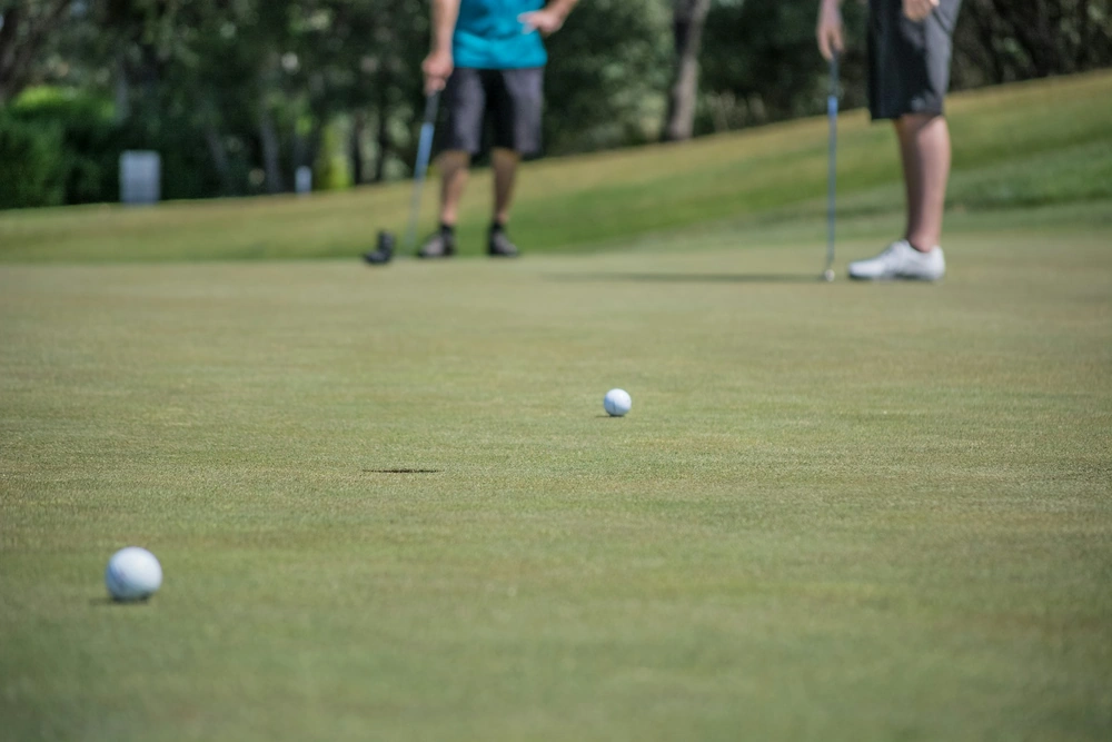 Golfeur évaluant la distance d'un putt long sur green pour maîtriser le dosage et éviter les trois-putts