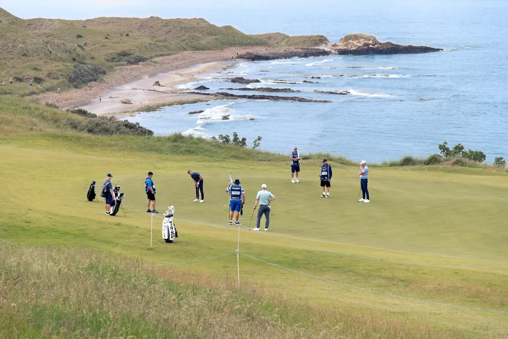 Putting green d'un links côtier avec golfeurs au-dessus de l'océan