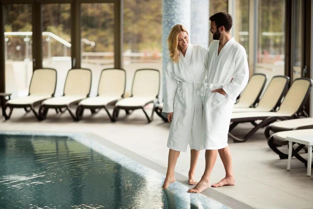 Couple en peignoirs au bord d'une piscine de spa pour la récupération après une partie, séjour golf France