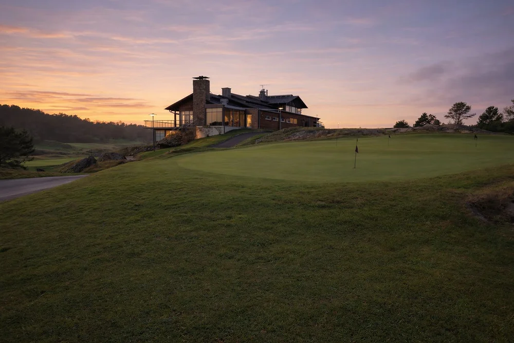 Club-house de resort golf au coucher de soleil avec green éclairé, séjour golf France en domaine intégré
