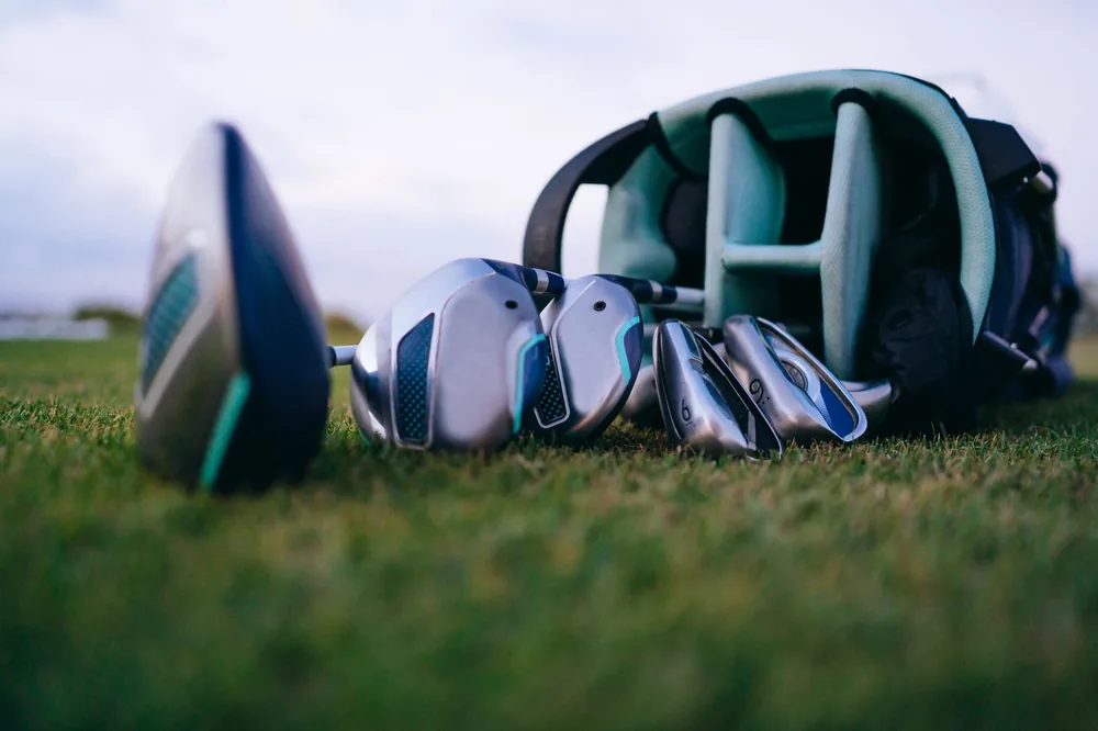 Clubs de golf posés sur l'herbe à côté d'un sac ouvert sur un terrain