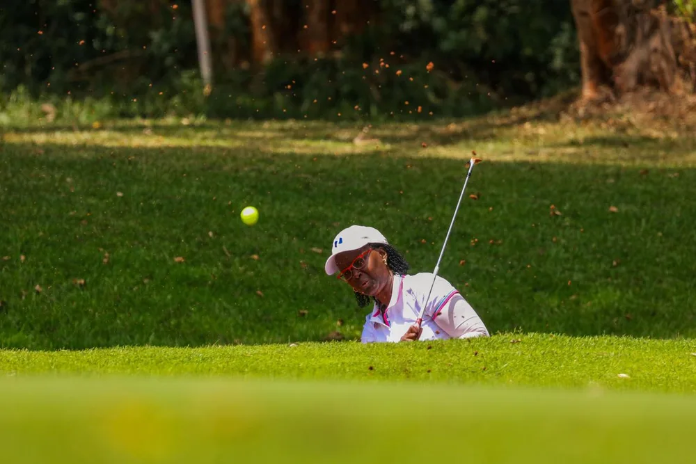 Une golfeuse joue une sortie de bunker tandis que la balle s’élève devant elle.