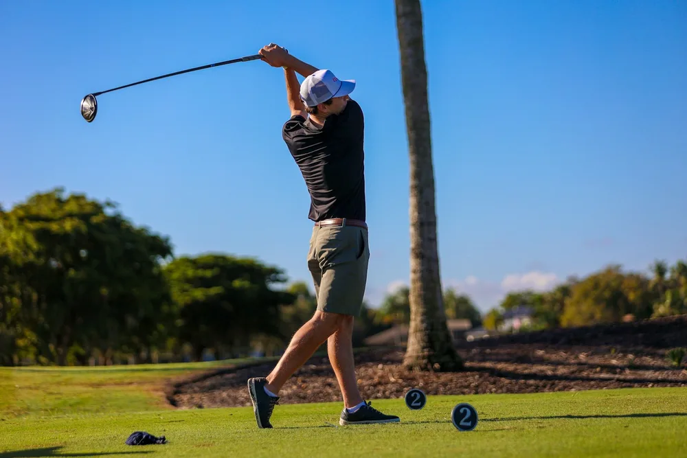 Un homme frappant une balle de golf avec un club de golf