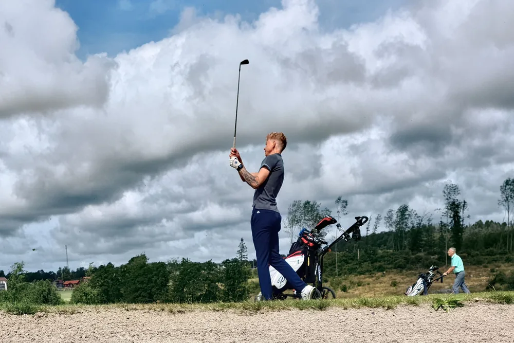 Golfeur en position de finish complet sur un parcours de golf par temps nuageux