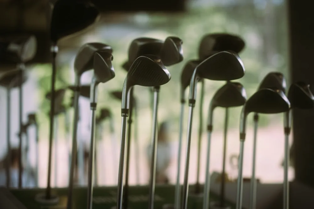 Plusieurs clubs de golf aux manches métalliques alignés dans un présentoir de practice