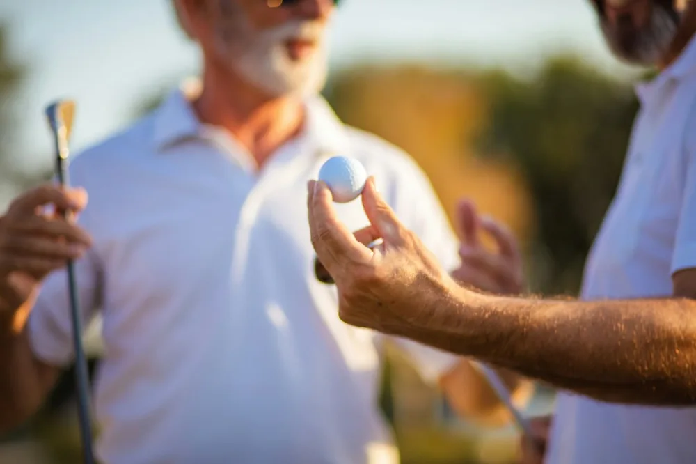 Des golfeurs seniors discutent de comment dropper une balle de golf avant de reprendre le jeu.